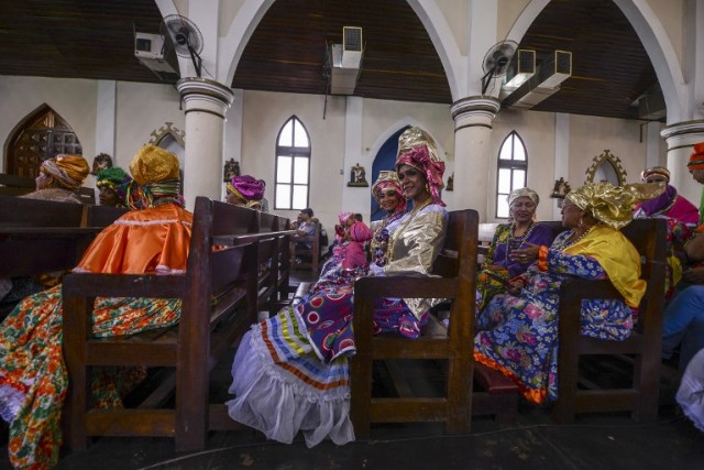 Women dressed as "madamas" attend a mass before the beginning of the Carnival in El Callao, in Bolivar state, Venezuela on February 26, 2017. El Callao's carnival was recently named Unesco's Intangible Cultural Heritage of Humanity and is led by the madamas, the pillars of Callaoense identity representing Antillean matrons considered the communicators of values, who dance and wear colourful dresses. / AFP PHOTO / JUAN BARRETO