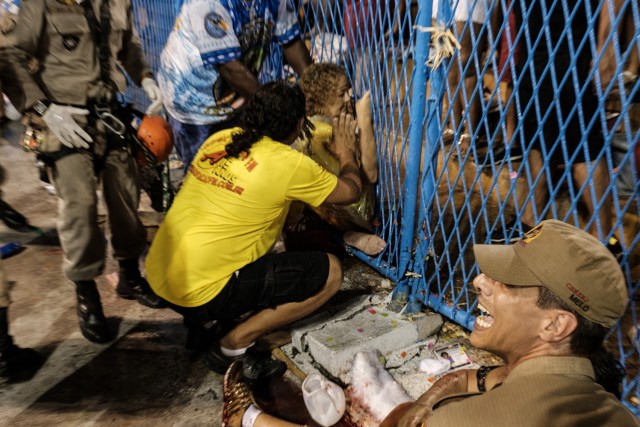 A woman in assisted by firefighters after being struck by a float of the Paraiso do Tuiuti samba school at the entrance of the Sambadrome during the first night of Rio's Carnival, in Rio de Janeiro, Brazil, on February 26, 2017. / AFP PHOTO / Yasuyoshi CHIBA