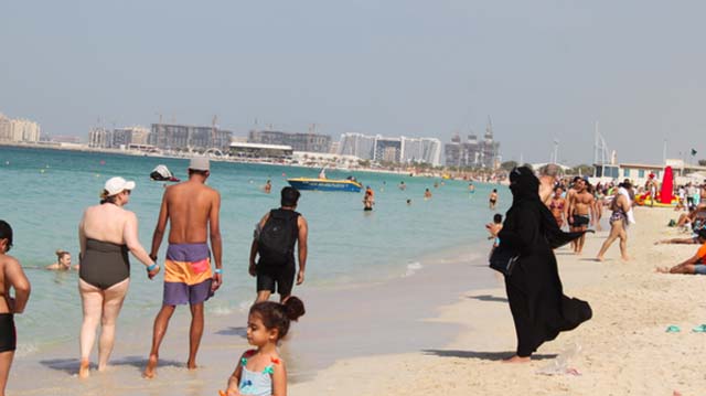 La imagen de impacto: mujeres musulmanas usan burka tradicional en medio de una playa occidentalizada y llena de turistas