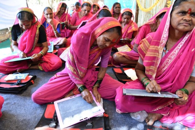 This photo taken on March 1, 2017 shows Indian grandmother Draupada Kedar (C), 62, and other classmates attending a class at Aajibaichi Shala, or "school for grannies" in the local Marathi language, in Phangane village in Maharashtra state's Thane district, some 125km northeast of Mumbai. They wear uniforms, carry satchels, and eagerly recite the alphabet in class, but the students here are different -- this is a "school for grannies". Deprived of an education as children, the women -- most of whom are widows and aged between 60 and 90 -- are finally fulfilling a life-long dream to become literate through this unique initiative near Mumbai. / AFP PHOTO / Indranil MUKHERJEE / TO GO WITH "India-education-women-school,FEATURE" by Peter HUTCHISON