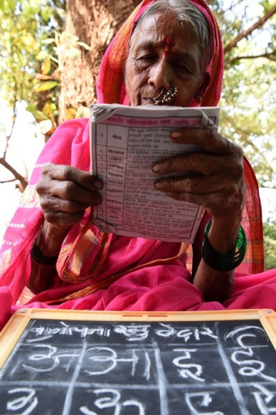 This photo taken on March 1, 2017 shows Indian grandmother Sulochona Kedar (C), 68, attending a class at Aajjibaichi Shala, or "school for grannies" in the local Marathi language, in Phangane village in Maharashtra state's Thane district, some 125km northeast of Mumbai. They wear uniforms, carry satchels, and eagerly recite the alphabet in class, but the students here are different -- this is a "school for grannies". Deprived of an education as children, the women -- most of whom are widows and aged between 60 and 90 -- are finally fulfilling a life-long dream to become literate through this unique initiative near Mumbai. / AFP PHOTO / Indranil MUKHERJEE / TO GO WITH "India-education-women-school,FEATURE" by Peter HUTCHISON