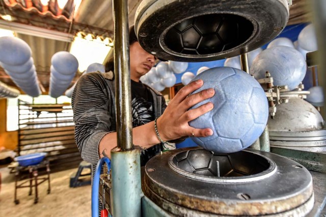 A worker handles inner tubes of footballs at a ball factory in Mongui, in the Colombian department of Boyaca, on February 13, 2017. Mongui, in the central mountains of Colombia, has about 20 football factories that make balls mainly for football and micro-football. About a quarter of the town's 4,900 inhabitants work in these factories. / AFP PHOTO / Luis ACOSTA