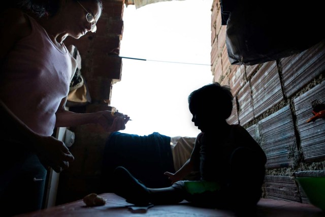 The mother of Venezuelan Rebeca Leon, who scavanges for food in the streets of Caracas, feeds her grandson at their house in Petare shantytown, on February 22, 2017. Venezuelan President Nicolas Maduro is resisting opposition efforts to hold a vote on removing him from office. The opposition blames him for an economic crisis that has caused food shortages.  / AFP PHOTO / FEDERICO PARRA / TO GO WITH AFP STORY by Alexander Martinez