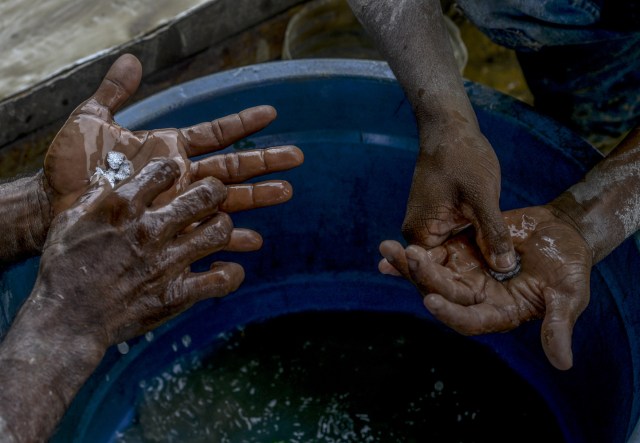 Men hold gold-mercury amalgam at a gold mine in El Callao, Bolivar state, southeastern Venezuela on February 25, 2017. Although life in the mines of eastern Venezuela is hard and dangerous, tens of thousands from all over the country head for the mines daily in overcrowded trucks, pushed by the rise in gold prices and by the severe economic crisis affecting the country, aggravated recently by the drop in oil prices. / AFP PHOTO / JUAN BARRETO