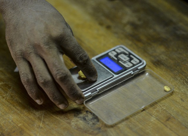 A man weighs a gold stone at a specialized store in El Callao, Bolivar state, southeastern Venezuela on February 25, 2017. Although life in the mines of eastern Venezuela is hard and dangerous, tens of thousands from all over the country head for the mines daily in overcrowded trucks, pushed by the rise in gold prices and by the severe economic crisis affecting the country, aggravated recently by the drop in oil prices. / AFP PHOTO / JUAN BARRETO