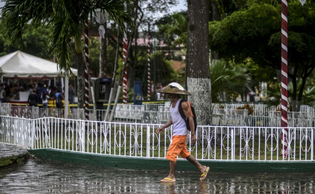 A gold miner with a pan on his head walks along one of the main avenues of El Callao, Bolivar state, southeastern Venezuela on February 25, 2017. Although life in the mines of eastern Venezuela is hard and dangerous, tens of thousands from all over the country head for the mines daily in overcrowded trucks, pushed by the rise in gold prices and by the severe economic crisis affecting the country, aggravated recently by the drop in oil prices. / AFP PHOTO / JUAN BARRETO