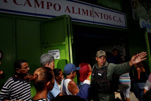 A Venezuelan soldier tries to control the crowd as people queue to buy food outside a market in Caracas, Venezuela July 19, 2016. REUTERS/Carlos Garcia Rawlins    SEARCH "GARCIA QUEUEING" FOR THIS STORY. SEARCH "WIDER IMAGE" FOR ALL STORIES.