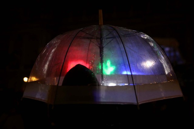 A man stands in the rain after the lights were switched off for Earth Hour at the Royal Palace in Madrid, Spain, March 25, 2017. REUTERS/Susana Vera