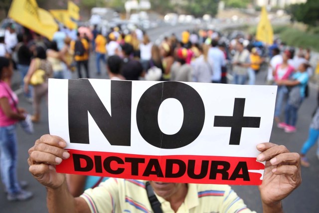 Opposition supporters holding a placard that reads, "No more dictatorship" shout slogans as they block a highway during a protest against Venezuelan President Nicolas Maduro's government in Caracas, Venezuela March 31, 2017. REUTERS/Carlos Garcia Rawlins