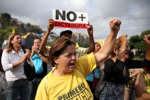 Opposition supporters holding a placard that reads, "No more dictatorship" shout slogans as they block a highway during a protest against Venezuelan President Nicolas Maduro's government in Caracas, Venezuela March 31, 2017. REUTERS/Carlos Garcia Rawlins