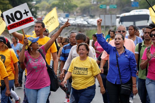 Opposition supporters holding a placard that reads, "No more dictatorship" shout slogans as they block a highway during a protest against Venezuelan President Nicolas Maduro's government in Caracas, Venezuela March 31, 2017. REUTERS/Carlos Garcia Rawlins