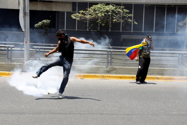 A demonstrator kicks a gas canister during an opposition rally in Caracas, Venezuela