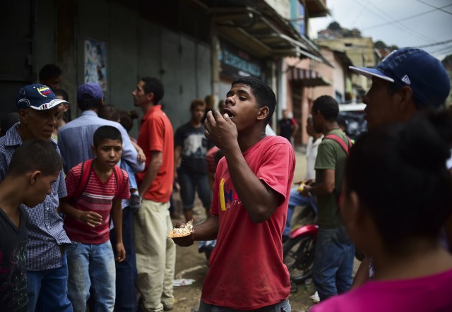 A man eats food he found outside a looted supermarket at El Valle neighborhood, in Caracas, on April 21, 2017, after demonstrations against the government of Venezuelan President Nicolas Maduro. Venezuela was rocked overnight by fresh violence in anti-government protests that have now claimed nine lives in three weeks, as an official reported Friday the fatal shooting of another man. / AFP PHOTO / RONALDO SCHEMIDT