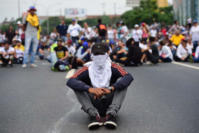 Venezuelan opposition activists block organize a sit-in to block the Francisco Fajardo motorway in Caracas, on April 24, 2017. Protesters plan Monday to block Venezuela's main roads including the capital's biggest motorway, triggering fears of further violence after three weeks of unrest left 21 people dead. / AFP PHOTO / RONALDO SCHEMIDT