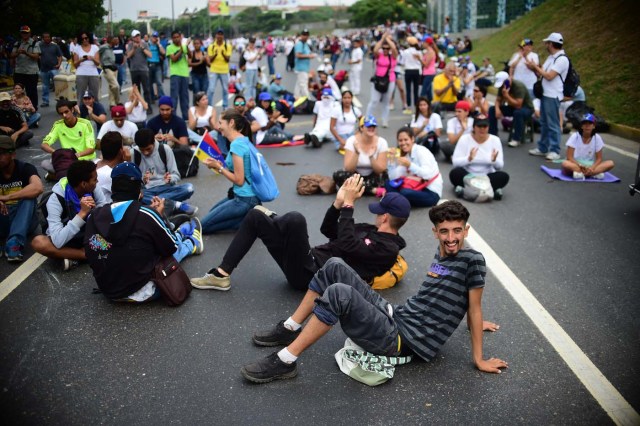 Venezuelan opposition activists block organize a sit-in to block the Francisco Fajardo motorway in Caracas, on April 24, 2017. Protesters plan Monday to block Venezuela's main roads including the capital's biggest motorway, triggering fears of further violence after three weeks of unrest left 21 people dead. / AFP PHOTO / RONALDO SCHEMIDT