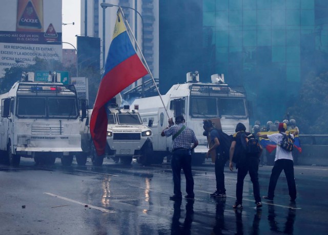 An opposition supporter waves a Venezuelan flag in front of the riot police during a rally against Venezuela's President Nicolas Maduro in Caracas, Venezuela April 26, 2017. REUTERS/Carlos Garcia Rawlins