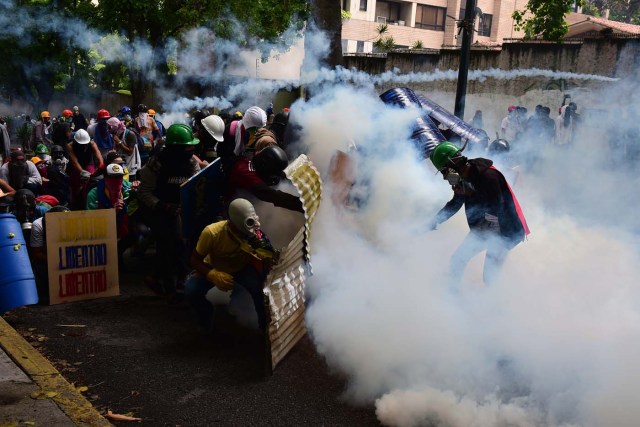 Venezuelan opposition activists clash with the police during a march against President Nicolas Maduro, in Caracas on May 1, 2017. Security forces in riot vans blocked off central Caracas Monday as Venezuela braced for pro- and anti-government May Day protests one month after a wave of deadly political unrest erupted.  / AFP PHOTO / RONALDO SCHEMIDT