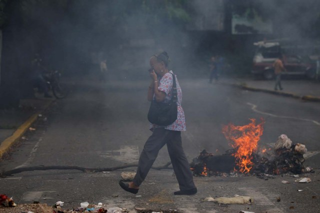 A woman covers her face as she walks past a burning barricade during a protest against Venezuela's President Nicolas Maduro's government in Caracas, Venezuela May 2, 2017. REUTERS/Carlos Garcia Rawlins