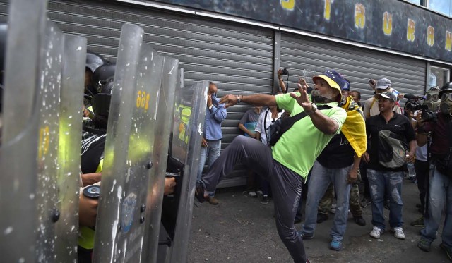 Opposition activists clash with riot police during a protest against the government in Caracas on May 12, 2017. Daily clashes between demonstrators -who blame elected President Nicolas Maduro for an economic crisis that has caused food shortage- and security forces have left 38 people dead since April 1. Protesters demand early elections, accusing Maduro of repressing protesters and trying to install a dictatorship. / AFP PHOTO / JUAN BARRETO