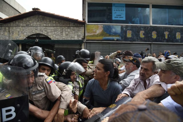 Opposition activists confront riot police during a protest against the government in Caracas on May 12, 2017. Daily clashes between demonstrators -who blame elected President Nicolas Maduro for an economic crisis that has caused food shortage- and security forces have left 38 people dead since April 1. Protesters demand early elections, accusing Maduro of repressing protesters and trying to install a dictatorship. / AFP PHOTO / JUAN BARRETO