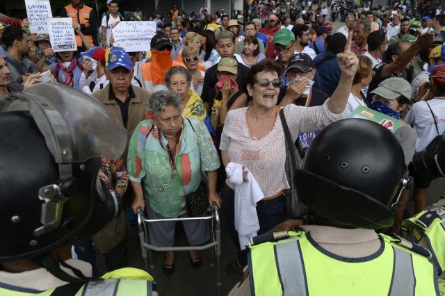 Opposition activists confront riot police during a protest against the government in Caracas on May 12, 2017. Daily clashes between demonstrators -who blame elected President Nicolas Maduro for an economic crisis that has caused food shortage- and security forces have left 38 people dead since April 1. Protesters demand early elections, accusing Maduro of repressing protesters and trying to install a dictatorship. / AFP PHOTO / FEDERICO PARRA