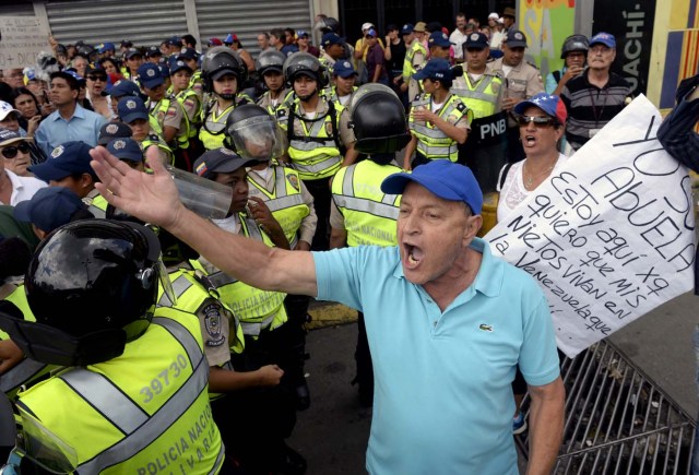 Opposition activists confront riot police during a protest against the government in Caracas on May 12, 2017. Daily clashes between demonstrators -who blame elected President Nicolas Maduro for an economic crisis that has caused food shortage- and security forces have left 38 people dead since April 1. Protesters demand early elections, accusing Maduro of repressing protesters and trying to install a dictatorship. / AFP PHOTO / FEDERICO PARRA