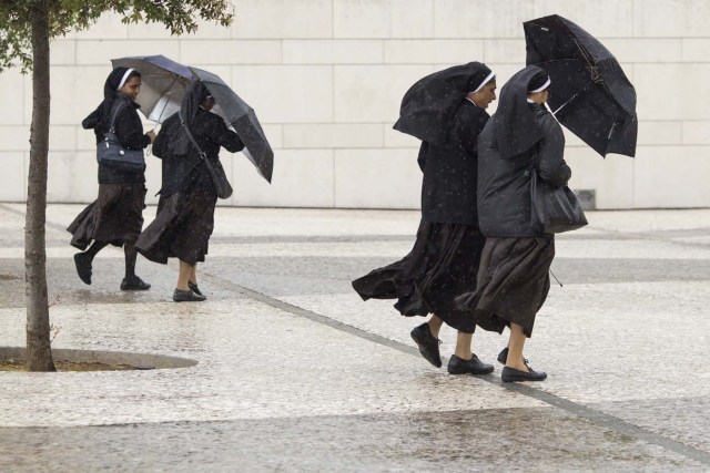 PAC01 FÁTIMA (PORTUGAL), 10/05/2017.- Cuatro monjas se protegen de la lluvia en el santuario de Fátima, Portugal, hoy, 10 de mayo de 2017. El papa Francisco afirmó hoy durante la audiencia que en su visita los próximo viernes y sábado al santuario de Fátima pondrá en manos de la Virgen "el destino temporal y eterno de la humanidad". EFE/Paulo Cunha