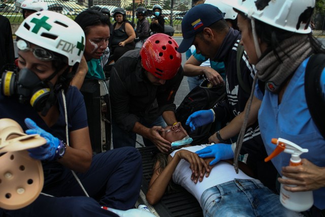 VEN053. CARACAS (VENEZUELA), 24/05/2017-. Una manifestante desmayada por los gases lacrimógenos es auxiliada por rescatistas hoy, miércoles 24 de mayo de 2017, durante una protesta contra el Gobierno en Caracas (Venezuela). Una manifestación convocada por la oposición venezolana en Caracas terminó hoy con 62 lesionados, entre ellos un diputado opositor y tres heridos por arma de fuego, informó el director de salud del municipio caraqueño Baruta, Enrique Montbrun. EFE/CRISTIAN HERNANDEZ