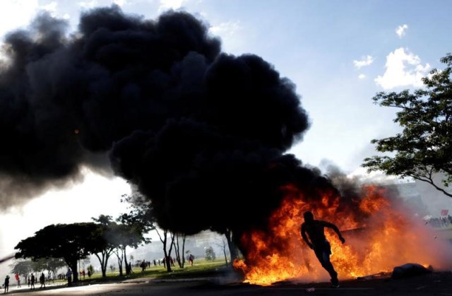 Un manifestante corre cerca de una barricada durante una protesta contra el presidente de Brasil, Michel Temer, en Brasilia. 24 de mayo de 2017. El Gobierno de Brasil revocó el jueves un decreto presidencial que permitió el despliegue de soldados en la capital del país para contener a manifestantes que protestaban contra el presidente Michel Temer y sus medidas de austeridad. REUTERS/Ueslei Marcelino