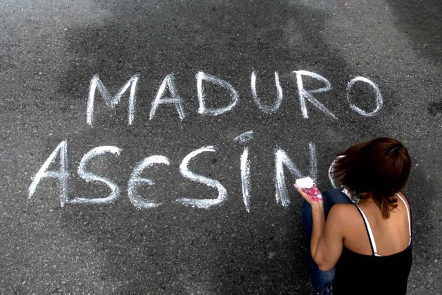 CAR03. CARACAS (VENEZUELA), 16/06/2017.- Una mujer escribe un mensaje sobre el asfalto durante una manifestación hoy, viernes 16 de junio de 2017, en Caracas (Venezuela). Los estudiantes de la universidad privada Alejandro de Humboldt (UAH) protestaron hoy en Caracas para rechazar la entrega de sus datos personales al Poder Electoral por parte del rector de la casa de estudios lo que, especulan, será usado para respaldar la asamblea constituyente propuesta por el Gobierno. EFE/Miguel Gutiérrez