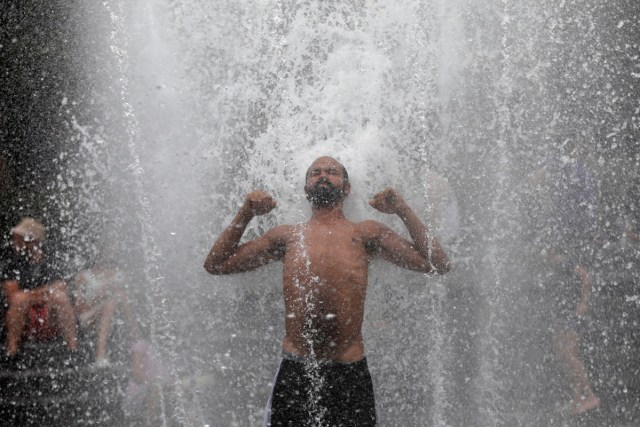 A man gets relief from hot weather as he cools off in a fountain in Washington Square Park in the Manhattan borough of New York City, U.S., July 13, 2017. REUTERS/Mike Segar