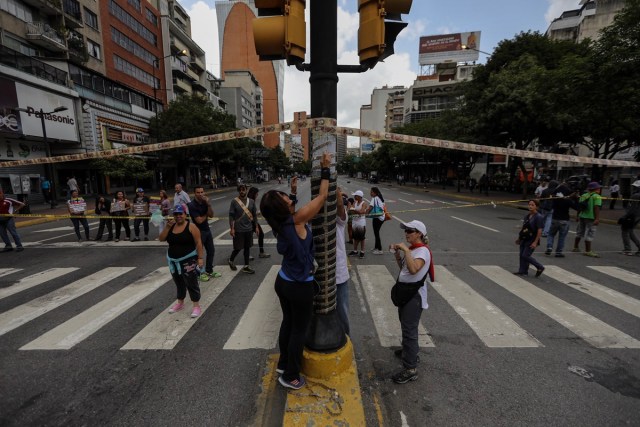 CAR113. CARACAS (VENEZUELA), 10/07/2017.- Manifestantes bloquean una vía con cintas hechas de monedas y billetes hoy, lunes 10 de julio de 2017, en Caracas (Venezuela). Los opositores venezolanos atendieron hoy a la convocatoria de realizar un "trancazo" de calles en todo el país contra la "dictadura" que se espera se extienda por diez horas, después de que la alianza antichavista intentara reducir esta protesta a solo dos horas. EFE/Miguel Gutiérrez