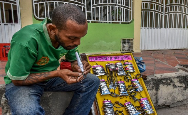 El venezolano Ernesto Toro realiza la venta de brazaletes en espera de comida y refugio frente al Centro de Migración de Cucuta, al norte del departamento de Santander, Colombia, el 26 de julio de 2018. Unos 25.000 venezolanos cruzan a Colombia y regresan a su país diariamente Con alimentos, consumibles y dinero de trabajo ilegal, según fuentes oficiales. Además, hay 47.000 venezolanos en Colombia con estatus migratorio legal y otros 150.000 que ya han completado los 90 días permitidos y ahora están sin visa. Luis Acosta / AFP