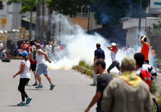 Opposition supporters run past a tear gas cloud as clashes broke out while the Constituent Assembly election was being carried out in Caracas, Venezuela, July 30, 2017. REUTERS/Christian Veron