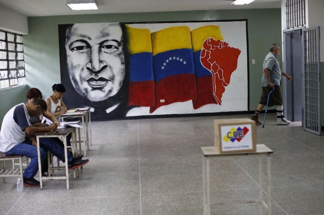 Electoral officials work as a man departs after casting his vote at a polling station during the Constituent Assembly election in Caracas, Venezuela, July 30, 2017. REUTERS/Carlos Garcia Rawlins