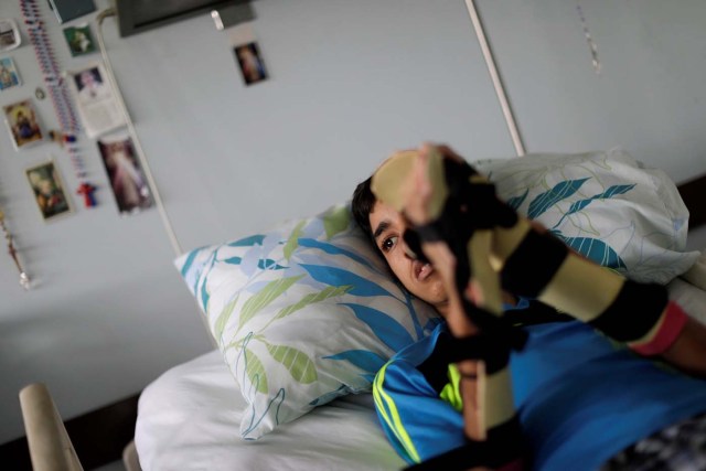 Oscar Antonio Navarrete, 18, a student, who was injured during a protest against Venezuela's President Nicolas Maduro's government, lies in a hospital bed, in Caracas, Venezuela, August 17, 2017. Relatives of Navarrete said he was hit in the chest by a tear gas canister on May 18, 2017. He lost consciousness and his heart stopped for several minutes. He cannot walk, suffers short-term memory loss, severe motor sequelae and has cerebral edema - an accumulation of fluid in the brain. Today, he lives in a hospital and needs rehabilitation and treatment by specialist doctors including neurosurgeons, speech therapists and psychologists. Oscar's mother says her son was angry about crisis in the country, and protested because it affected everyone. "It was worth it, because none of this will be forgotten. The world needs to see all this, I have faith that things will change," said Navarrete's mother Elizabeth. REUTERS/Ueslei Marcelino SEARCH "VENEZUELA INJURIES" FOR THIS STORY. SEARCH "WIDER IMAGE" FOR ALL STORIES.