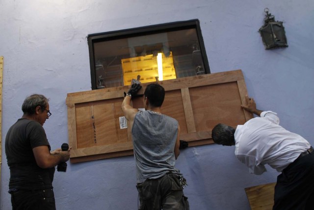 People board up windows of a business in preparation for the anticipated arrival of Hurricane Maria in San Juan, Puerto Rico on September 18, 2017. Hurricane Maria has grown into a maximum-strength Category Five storm, US forecasters said Monday, as it was bearing down on the Caribbean island of Dominica. / AFP PHOTO / Ricardo ARDUENGO