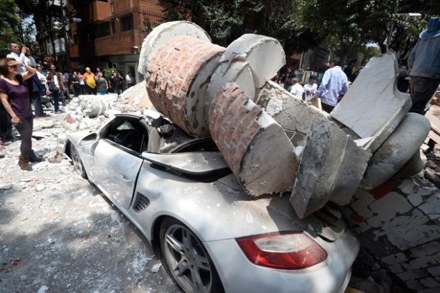 Picture of a car crashed by debris from a damaged building after a quake rattled Mexico City on September 19, 2017. A powerful earthquake shook Mexico City on Tuesday, causing panic among the megalopolis' 20 million inhabitants on the 32nd anniversary of a devastating 1985 quake. The US Geological Survey put the quake's magnitude at 7.1 while Mexico's Seismological Institute said it measured 6.8 on its scale. The institute said the quake's epicenter was seven kilometers west of Chiautla de Tapia, in the neighboring state of Puebla. / AFP PHOTO / Alfredo ESTRELLA