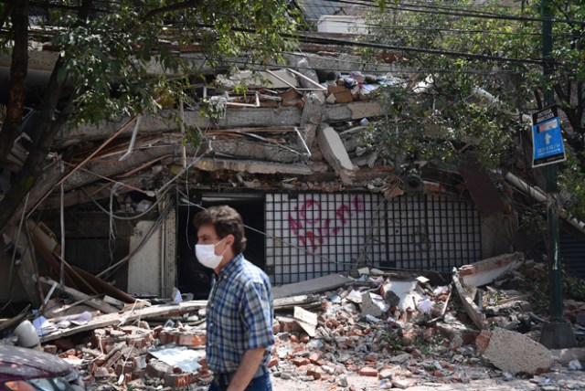 A man walks past a building which collapsed during a quake in Mexico City on September 19, 2017. A powerful earthquake shook Mexico City on Tuesday, causing panic among the megalopolis' 20 million inhabitants on the 32nd anniversary of a devastating 1985 quake. The US Geological Survey put the quake's magnitude at 7.1 while Mexico's Seismological Institute said it measured 6.8 on its scale. The institute said the quake's epicenter was seven kilometers west of Chiautla de Tapia, in the neighboring state of Puebla. / AFP PHOTO / Ronaldo SCHEMIDT