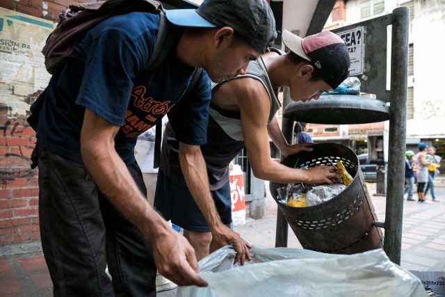 ACOMPAÑA CRÓNICA: VENEZUELA CRISIS. CAR05. CARACAS (VENEZUELA), 25/09/2017.- Fotografía fechada el 20 de septiembre de 2017 que muestra a dos hombres mientras hurgan en una basura en busca de comida en una calle de Caracas (Venezuela). En las calles de Caracas deambulan cada vez más niños y de menos edad. Se trata, según analistas y activistas de derechos humanos, de una nueva oleada de pequeños que prácticamente han abandonado sus hogares, aunque esta vez la razón es una sola: "La falta de comida en sus casas". EFE/Miguel Gutiérrez