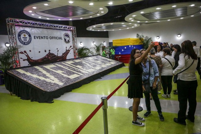 ACOMPAÑA CRÓNICA: VENEZUELA GASTRONOMÍA. CAR12. CARACAS (VENEZUELA), 29/09/2017.- Fotografía fechada el 28 de septiembre de 2017 que muestra a varias personas mientras se toman fotografías cerca del mosaico con barras de chocolate "más grande del mundo", con 18.56 metros de largo y conformado por 1635 barras de chocolate, en Caracas (Venezuela). La industria del chocolate en Venezuela organiza su V Expoferia Internacional para "darle impulso" exportador a sus productos, en medio de la rampante crisis económica que atraviesa el país petrolero, y con la mira puesta en otro récord Guinness que promocione el llamado "mejor cacao del mundo". EFE/Cristian Hernández