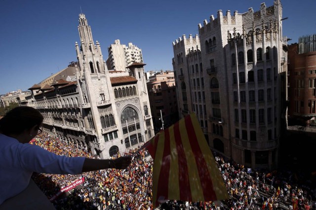 A protester holds a Catalan flag from a balcony during a demonstration called by "Societat Civil Catalana" (Catalan Civil Society) to support the unity of Spain on October 8, 2017 in Barcelona. Spain braced for more protests despite tentative signs that the sides may be seeking to defuse the crisis after Madrid offered a first apology to Catalans injured by police during their outlawed independence vote. / AFP PHOTO / PAU BARRENA