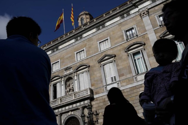 People walk past the Generalitat Palace in Barcelona on October 10, 2017. Spain's worst political crisis in a generation will come to a head as Catalonia's leader could declare independence from Madrid in a move likely to send shockwaves through Europe.  / AFP PHOTO / PAU BARRENA