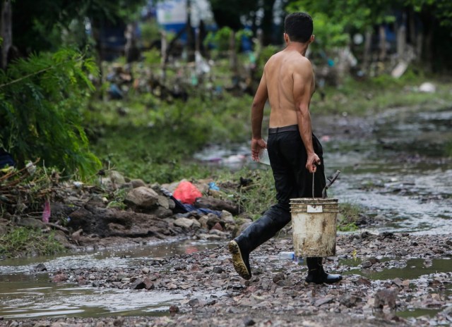 A man wades through a muddy street, following heavy rains in the Pacific Coast, in Teustepe, Boaco, some 60km from Managua, on October 26, 2017. / AFP PHOTO / INTI OCON