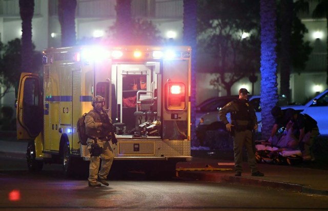 LAS VEGAS, NV - OCTOBER 01: Las Vegas Metropolitan Police Department officers stand near an ambulance as medical personnel treat a person in the parking lot of the Hooters Casino Hotel after a mass shooting at a country music festival nearby on October 1, 2017 in Las Vegas, Nevada. A gunman has opened fire on a music festival in Las Vegas, leaving at least 20 people dead and more than 100 injured. Police have confirmed that one suspect has been shot. The investigation is ongoing. Ethan Miller/Getty Images/AFP