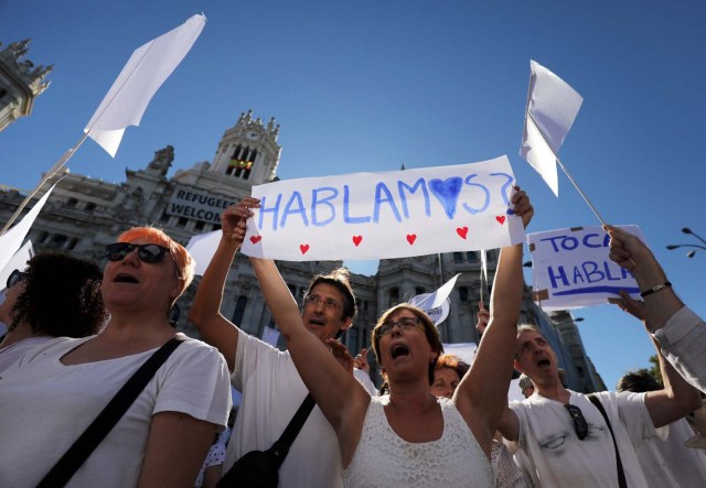 A couple hold a sign which reads "Shall we talk?" in Spanish during a demonstration in favour of dialogue to resolve Catalonia´s bid for independence, in Madrid, Spain, October 7, 2017. REUTERS/Sergio Perez