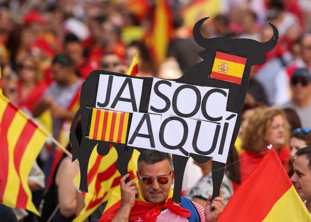 A man holds up a banner in the form of a bull reading "I am here" during a pro-union demonstration organised by the Catalan Civil Society organisation in Barcelona, Spain, October 8, 2017. REUTERS/Albert Gea