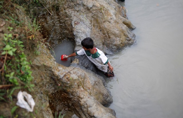 Una niño refugiado rohingya recoge agua de un pozo poco profundo, excavado en la arena a lo largo de un desagüe en el campo de refugiados de Uchiprang, cerca de Cox's Bazar, Bangladesh 29 de octubre de 2017. REUTERS / Adnan Abidi