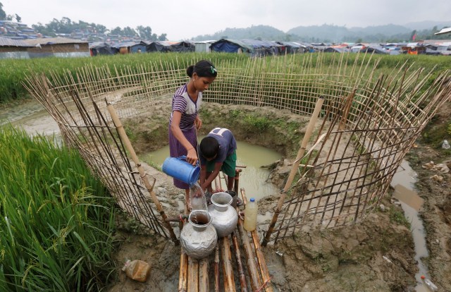 Los niños refugiados rohingya recogen agua de un pozo poco profundo, excavado en la arena fuera de su refugio en el campo de refugiados de Uchiprang cerca de Cox's Bazar, Bangladesh 29 de octubre de 2017. REUTERS / Adnan Abidi