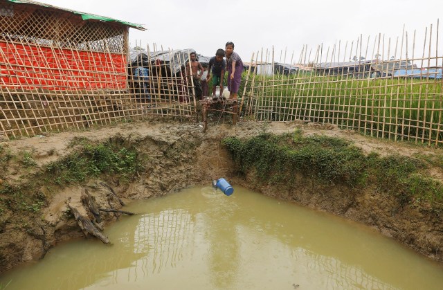 Los niños refugiados rohingya recogen agua de un pozo poco profundo, excavado en la arena fuera de su refugio en el campo de refugiados de Uchiprang cerca de Cox's Bazar, Bangladesh 29 de octubre de 2017. REUTERS / Adnan Abidi